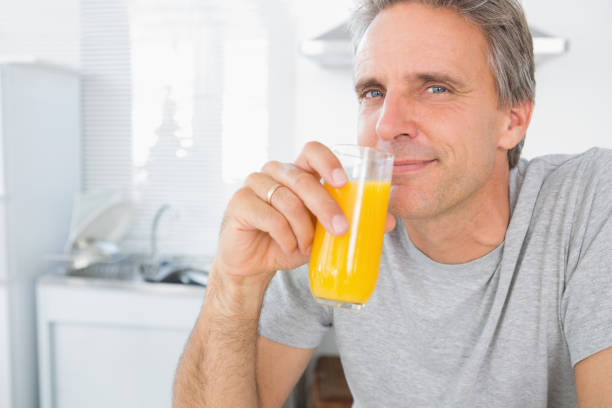 istock Happy man drinking orange juice in kitchen 847368486
