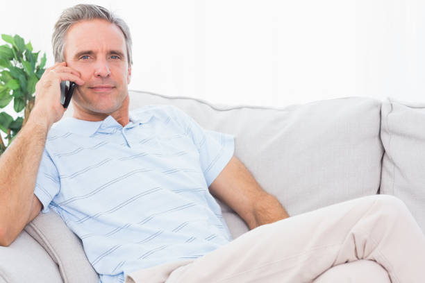 istock Man on his couch making phone call and smiling at camera 847371850