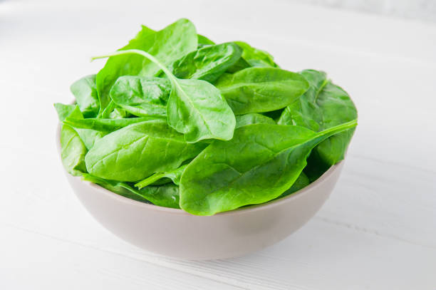 istock Fresh spinach leaves with water drops in ceramic bowl on thw white wooden background. Selective focus. Space for text 847371922