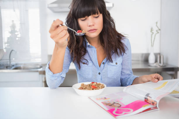 istock Pretty brunette having cereal and reading magazine 847404598