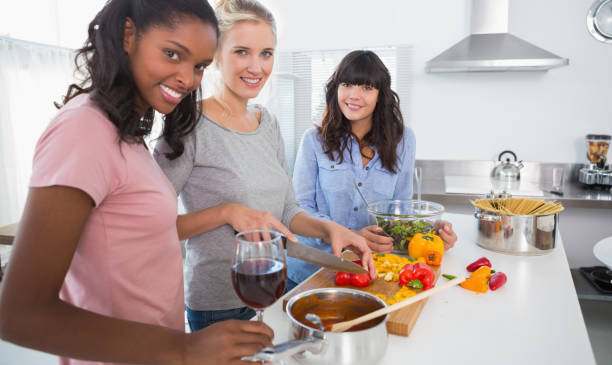 istock Smiling friends preparing a meal together looking at camera 847407384