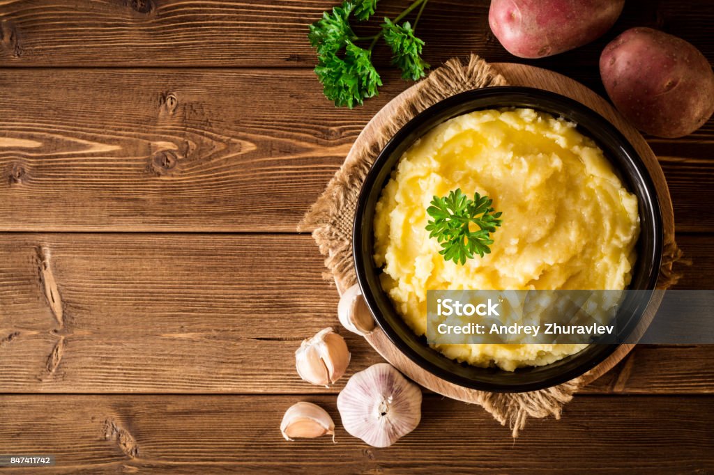 Mashed potatoes with butter and fresh parsley in bowl on rustic wooden table Mashed potatoes with butter and fresh parsley in bowl on rustic wooden table. Top view with copy space. Mashed Potatoes Stock Photo