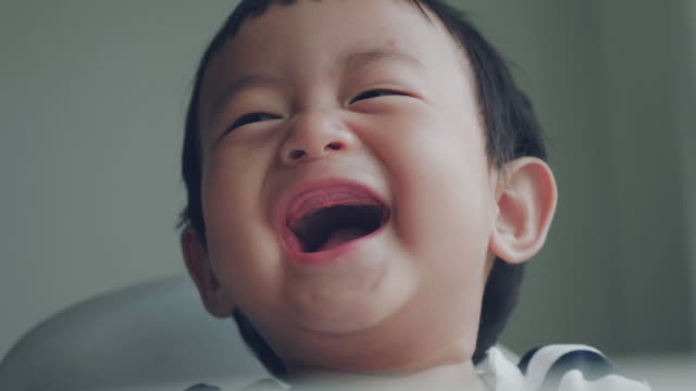 自宅で笑っているアジアの赤ちゃん(6-11ヶ月)の男の子のMSショット。バンコク。