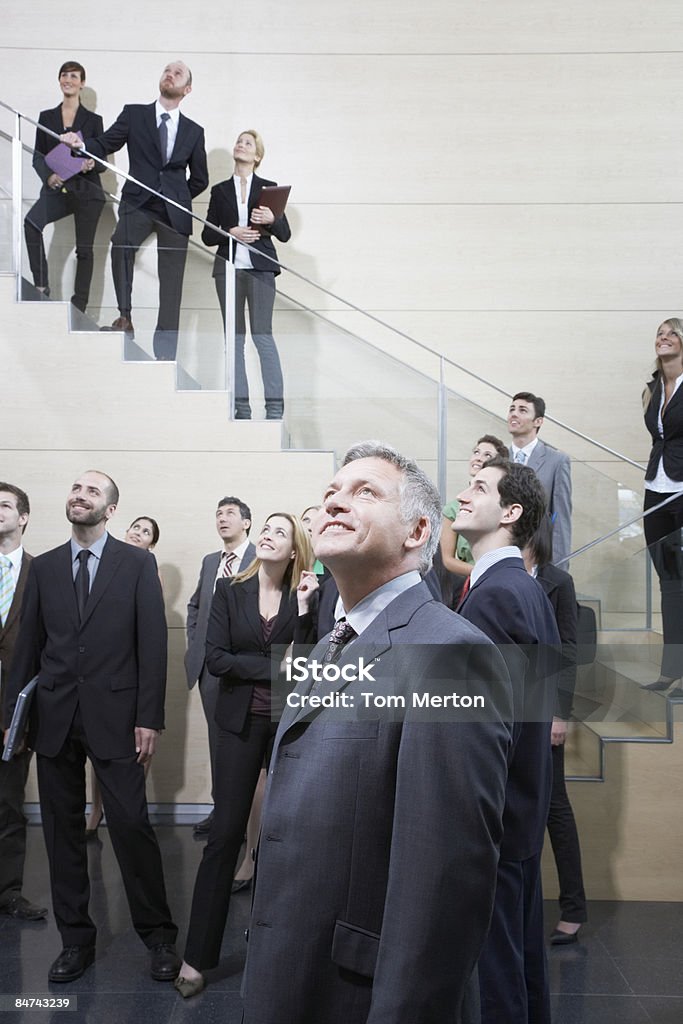 Businesspeople looking up in office lobby  Admiration Stock Photo