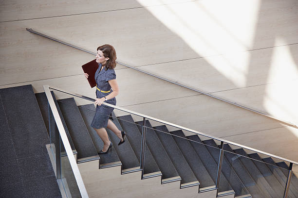 empresaria ascendente escalera de oficina - escalón y escalera fotografías e imágenes de stock