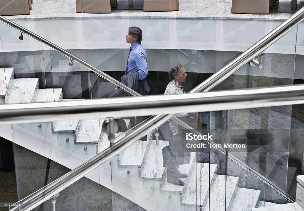 Hommes d'affaires en passant par les escaliers - Photo de Escalier libre de droits