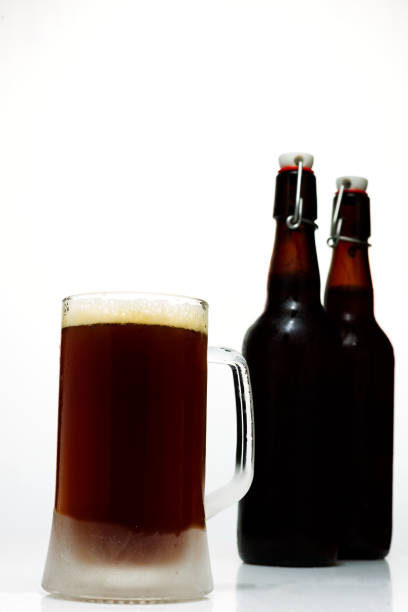 istock Beer glass with dark beer and two full beer bottles on a white background 847439028
