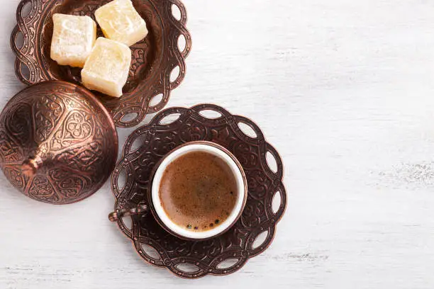 Traditional turkish coffee and turkish delight on white shabby wooden background. flat lay