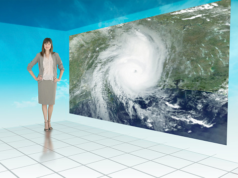 Businesswoman standing next to futuristic screen showing weather on a satellite map