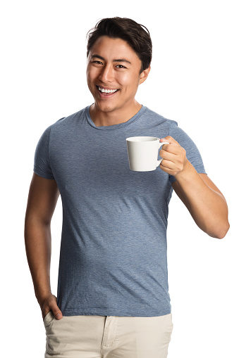 Smiling attractive man wearing a blue shirt and bright pants, holding a mug standing in front of a white background.