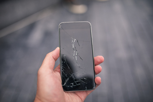 Man holding a broken smart phone in his hand, part of.