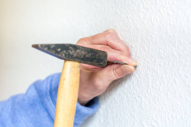 istock Hammer a nail into a white wall close up 847469484