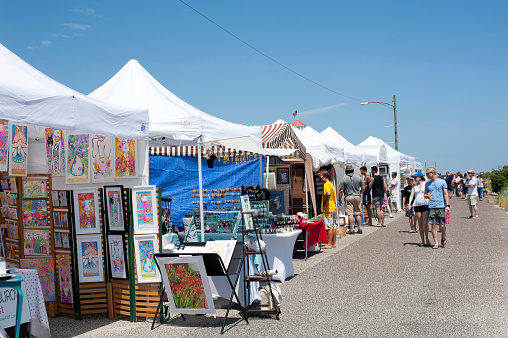 Cape May, USA - July 8, 2017. People walking past or stopping at art show booths on Beach Avenue in Cape May, New Jersey. Cape May is a historic Victorian seaside city at the tip of southern New Jersey's Cape May Peninsula. It attracts visitors for its grand Victorian houses, and shops and restaurants in Washington Street Mall besides the pristine beaches.