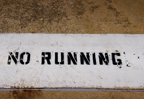 istock No Running sign painted beside a pool with wet footprints running across it 847502582