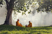 Two monks meditation under the trees with sun ray, Buddha religion concept