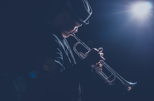 Musician playing the Trumpet with spot light and len flare on the stage