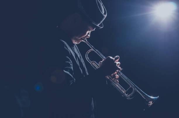 músico a tocar trompete com spot de luz e len flare no palco - trompa de caça - fotografias e filmes do acervo