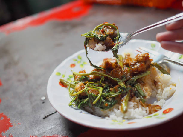 istock Spoon scooping stir fried water mimosa, crispy fried pork belly, oyster sauce on rice 847513622