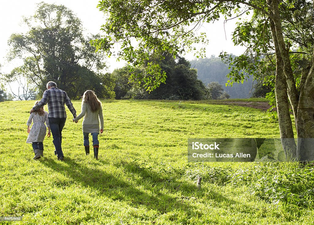 Famiglia a piedi una collina erbosa giustamente definita insieme - Foto stock royalty-free di Famiglia