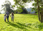 Family walking up a grassy hill together 