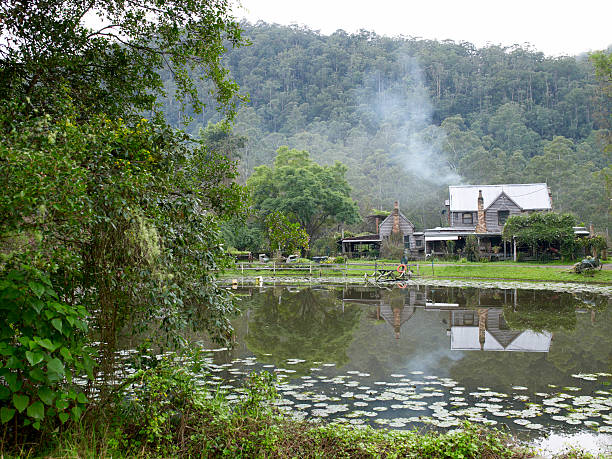 landhaus auf einem teich mit rauchen schornsteine - yarramalong stock-fotos und bilder