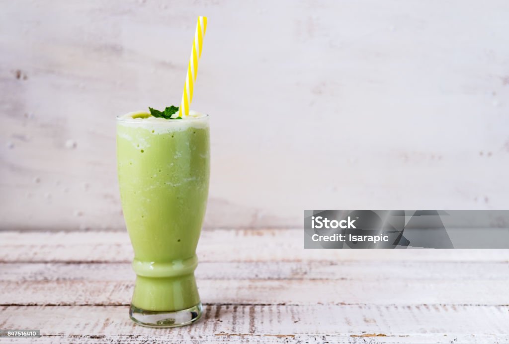 a glass of green tea smoothie a glass of green tea smoothie on white wooden board Smoothie Stock Photo