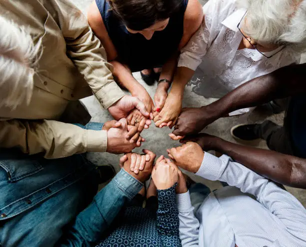 Photo of Group of diverse hands holding each other support together teamwork aerial view