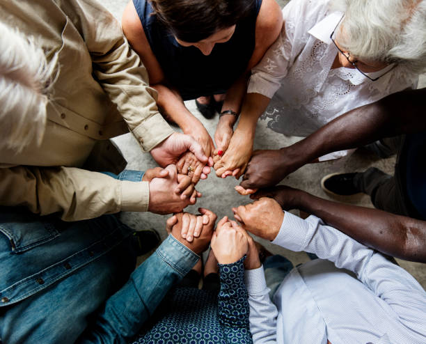 group of diverse hands holding each other support together teamwork aerial view - rezando imagens e fotografias de stock
