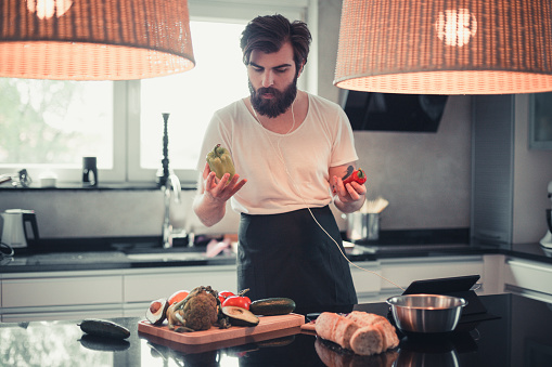 Handsome bearded man cooking and listening to music in the kitchen