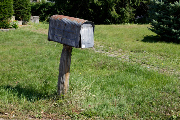 istock Rusted vintage country mailbox with spruce trees and grass in daylight 847534090