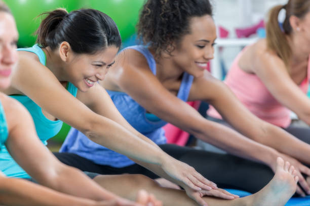 istock Cheerful Asian woman struggles to touch toes during exercise class 847535656