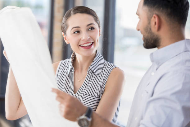 istock Cheerful female architect shows blueprint to male client 847535852