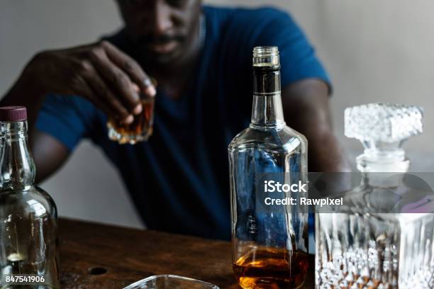 African Descent Man Sitting Drinking Whiskey Alcoholic Addiction Bad Habit Stock Photo - Download Image Now