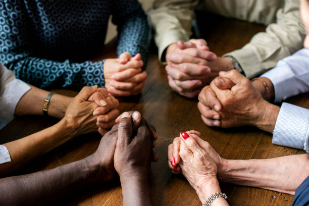 istock Group of interlocked fingers praying together 847549300