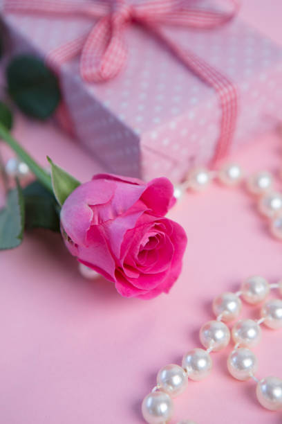 istock Pink rose with gift and pearls 847557312