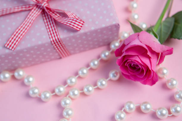 istock Pink rose with gift and string of pearls 847557334
