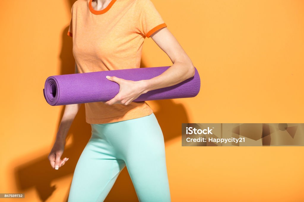 Yoga girl with yoga mat Yoga girl with yoga mat hurring to yoga class isolated over orange background Active Lifestyle Stock Photo