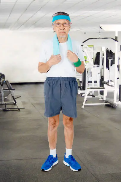 Portrait of an elderly man wearing sportswear while standing in the fitness center