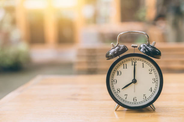 istock clock on wood table with green nature background time at 8 o'clock morning 847572008