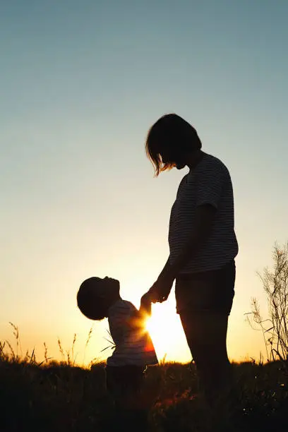 Photo of Silhouette of a woman with her child at sunset.