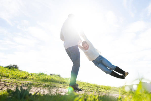 istock Father swinging child around in a field 847584280