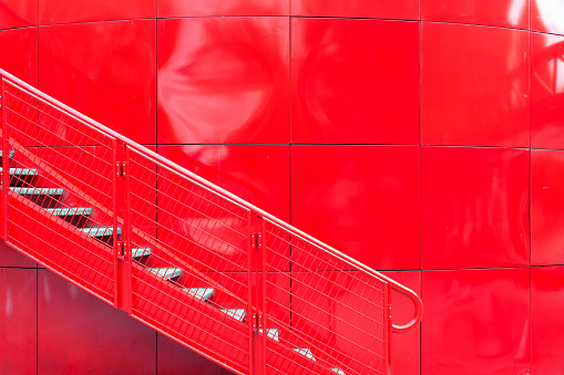 Metal ladder against the background of a red reservoir in an uneven surface