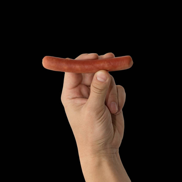 Sausage in a hand on a black background