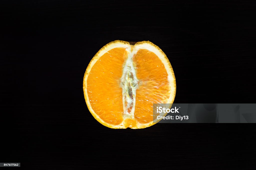 cut half an orange on a wooden table. cut half an orange on a wooden table on a dark background Orange - Fruit Stock Photo
