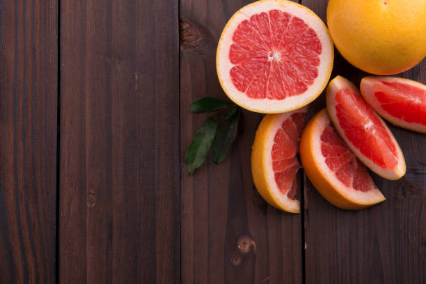 istock Ripe grapefruit slice on brown wooden background 847621576