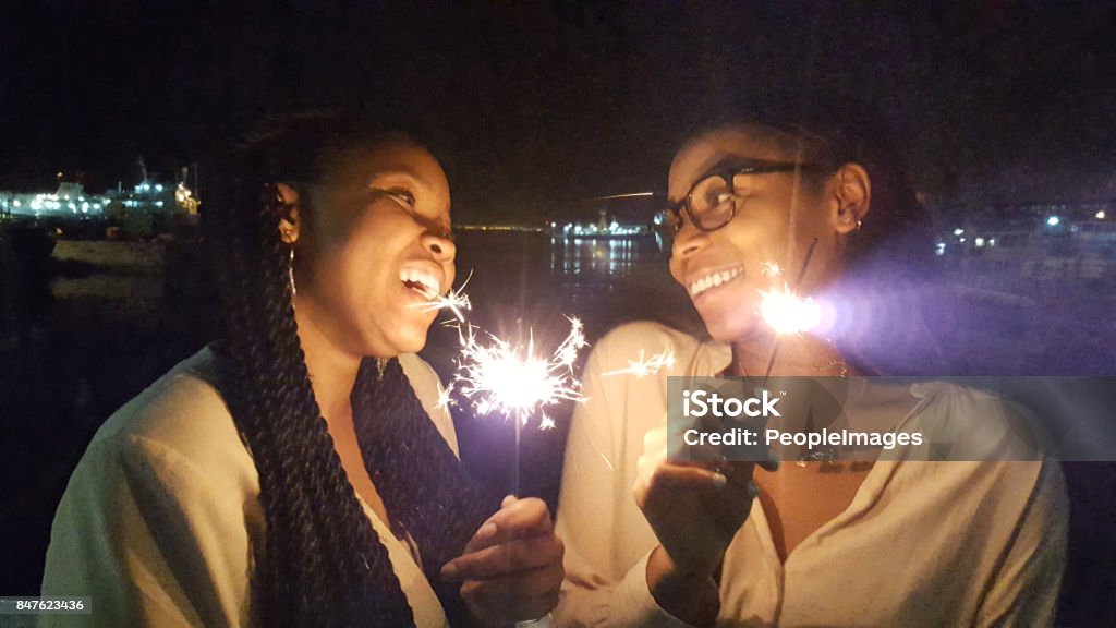 Best friends add sparkle to your life Shot of two young women having fun together with sparklers African Ethnicity Stock Photo