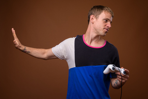 Studio shot of man playing video games against colored background horizontal shot