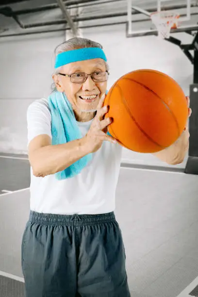 Portrait of an elderly man wearing sportswear while playing a basketball on the basketball court