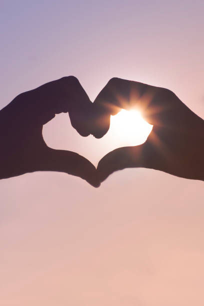 istock Love shape hands silhouette in sky with sun shining 847629222