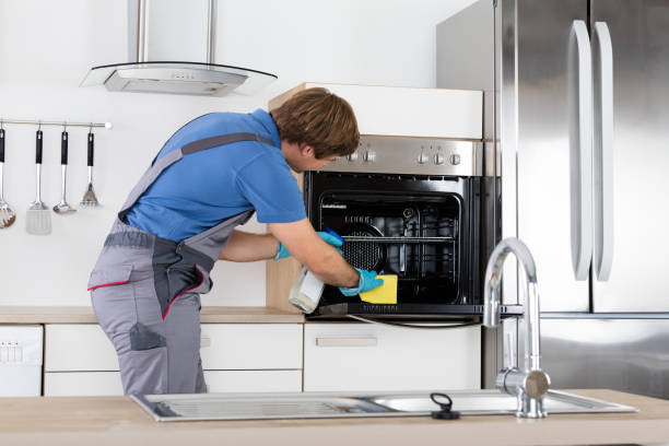 istock Man In Overall Cleaning Oven 847629376